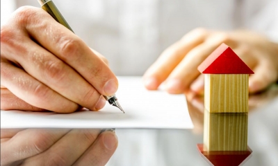 A hand signs a contract agreeing to release the equity in a home