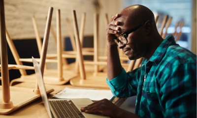 Business owner looking at his cashflow on his mac in his restaurant looking stressed