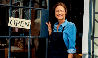 Happy woman owner showing open sign in her small business shop.