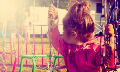 Young girls sits on a swing looking behind her