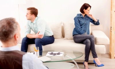 Man and woman sit on a white sofa with their backs to each other