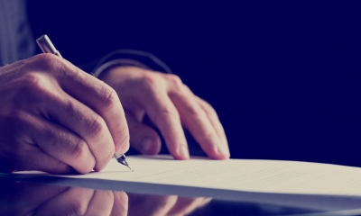 Wills Close up of hand holding a pen signing a piece of paper